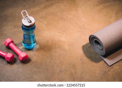 Sport equipment and bottle of water on wooden background