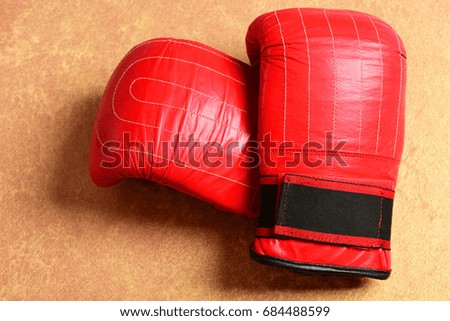 Sport equipment on warm beige paper background. Pair of leather boxing sportswear. Training and fitness concept. Boxing gloves in red color