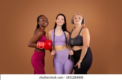 Sport For Every Body. Portrait Of Multiethnic Female Friends In Sportswear, Beautiful Ladies Of Different Sizes And Appearances Posing With Sport Equipment Over Brown Background In Studio, Copy Space - Powered by Shutterstock