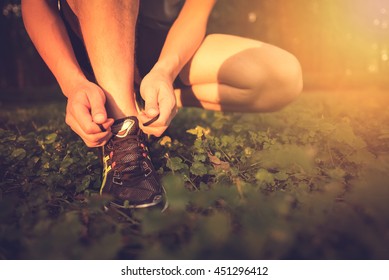 Sport Exercise, Fitness, Workout. Young Athlete, Runner Tie Shoelaces In Shoes. Outdoor Activity, Endurance. Active Person  Road Training. Healthy Lifestyle. People In Motion On Sunset. 