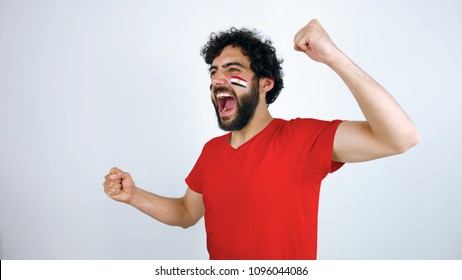 Sport Fan Screaming For The Triumph Of His Team. Man With The Flag Of Egypt Makeup On His Face And Red T-shirt.
       