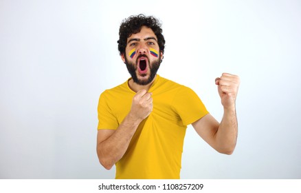 Sport Fan Screaming For The Triumph Of His Team. Man With The Flag Of Colombia Makeup On His Face And Yellow T-shirt.
           