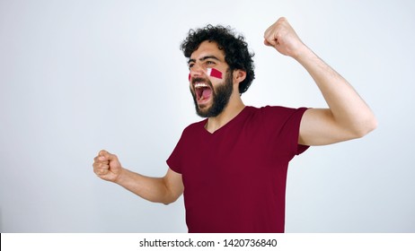 Sport Fan Screaming For The Triumph Of His Team. Man With The Flag Of Qatar Makeup On His Face And Purple T-shirt.