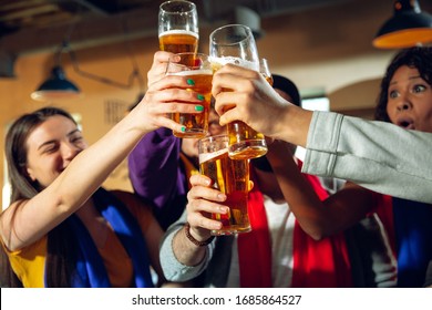 Sport fans cheering at bar, pub and drinking beer while championship, competition is going. Multiethnic group of friends excited watching translation. Human emotions, expression, supporting concept.