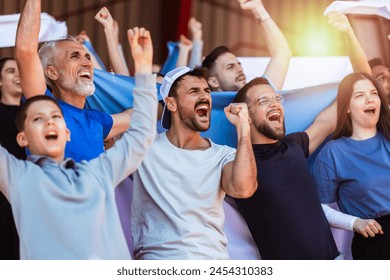 Sport fans cheering at the game on stadium. Wearing blue and white colors to support their team. Celebrating with flags and scarfs. - Powered by Shutterstock