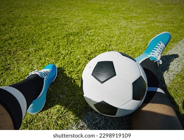 Sport, field and shoes of man with soccer ball outdoor, relax and resting after fitness or training. Football, pov and male player relaxing on grass at park after workout, match or sports performance - Powered by Shutterstock