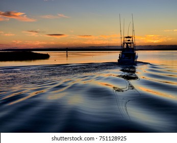 A sport fishing boat heading out of Wanchese harbor of the Outer Banks at dawn for a day of off-shore fishing.