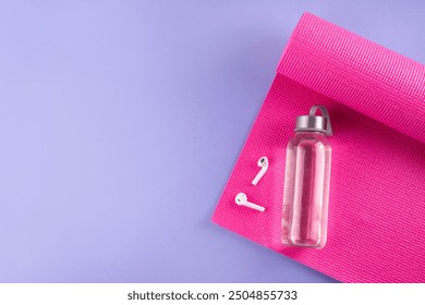 Sport and fitness background. Women's sports accessories. yoga mat with dumbbells, bottle of water, towel, jump rope, headphones, on light purple background, copy space - Powered by Shutterstock