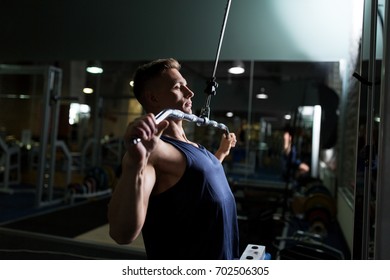 sport, fitness, bodybuilding, lifestyle and people concept - man exercising and flexing muscles on lat pull-down cable machine in gym