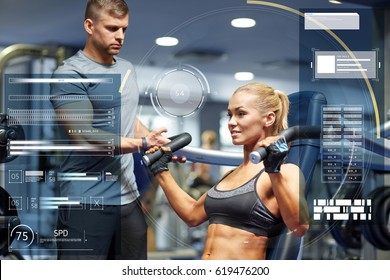 Sport, Fitness, Bodybuilding, Teamwork And People Concept - Young Woman And Personal Trainer Flexing Muscles On Gym Machine Over Virtual Charts