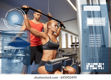 Sport, Fitness, Exercising And People Concept - Young Woman Flexing Muscles On Gym Machine And Personal Trainer With Clipboard Over Virtual Charts