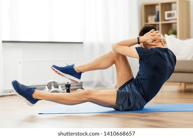 sport, fitness and healthy lifestyle concept - man making bicycle crunch on exercise mat and flexing abs at home - Shutterstock ID 1410668657