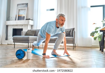 Sport, fitness and healthy lifestyle concept. Mature man doing exercises at home. How to stay healthy on quarantine concept. - Powered by Shutterstock