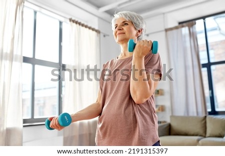 sport, fitness and healthy lifestyle concept - smiling senior woman with dumbbells exercising at home