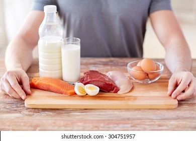 sport, fitness, healthy lifestyle, diet and people concept - close up of male hands with food rich in protein on cutting board on table - Powered by Shutterstock