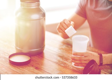 Sport, Fitness, Healthy Lifestyle And People Concept - Close Up Of Man In Fitness Bracelet With Jar And Bottle Preparing Protein Shake