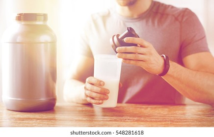 Sport, Fitness, Healthy Lifestyle And People Concept - Close Up Of Man In Fitness Bracelet With Jar And Bottle Preparing Protein Shake