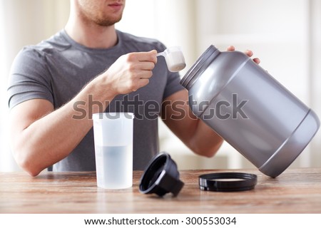 sport, fitness, healthy lifestyle and people concept - close up of man with jar and bottle preparing protein shake 商業照片 © 