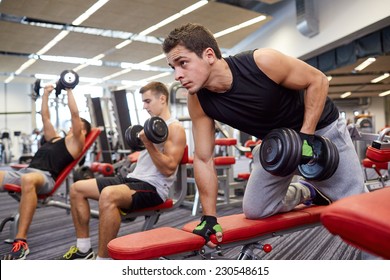 sport, fitness, lifestyle and people concept - group of men flexing muscles with dumbbells in gym
