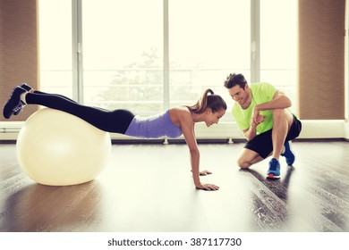sport, fitness, lifestyle and people concept - smiling man and woman working out with exercise ball in gym