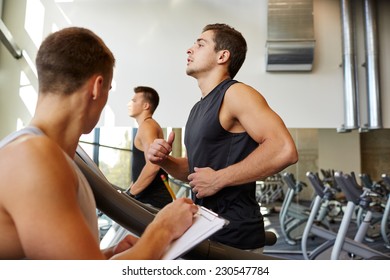 Sport, Fitness, Lifestyle, Technology And People Concept - Men With Personal Trainer Exercising On Treadmill In Gym