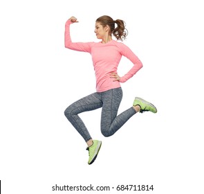 sport, fitness, motion and people concept - happy smiling young woman jumping in air and showing power gesture over white background