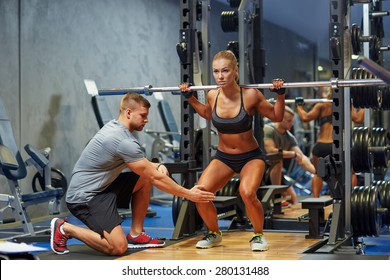 Sport, Fitness, Teamwork, Bodybuilding And People Concept - Young Woman And Personal Trainer With Barbell Flexing Muscles In Gym
