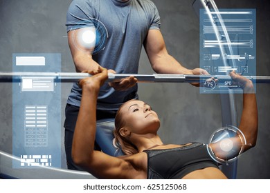 Sport, Fitness, Teamwork, Bodybuilding And People Concept - Young Woman And Personal Trainer With Barbell Flexing Muscles In Gym Over Virtual Charts