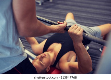 sport, fitness, teamwork, weightlifting and people concept - young man and personal trainer with barbell flexing muscles in gym