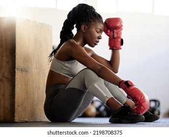 Sport, fitness and woman boxer on break from exercise and training on the floor of a gym. Black athlete looking exhausted with low energy during a routine workout. Female resting after physical match - Powered by Shutterstock