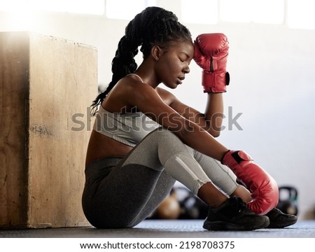 Sport, fitness and woman boxer on break from exercise and training on the floor of a gym. Black athlete looking exhausted with low energy during a routine workout. Female resting after physical match