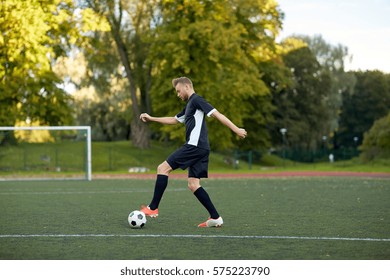 sport, football training and people - soccer player playing with ball on field - Shutterstock ID 575223790