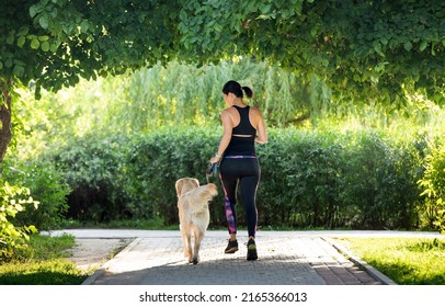 Sport girl running with golden retriever dog outdoors in the park. Young woman jogging with doggy pet labrador at summer - Shutterstock ID 2165366013