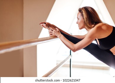 sport girl smiling and looking in mirror while stretching body in fitness class