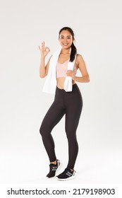 Sport, gym and healthy body concept. Full length of satisfied smiling female athlete, cute asian girl show okay gesture after good fitness training, workout exercises in gym, white background - Shutterstock ID 2179198903