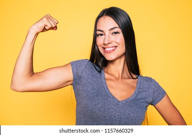 Sport, healthy lifestyle, gym, good body condition, women health, fitness concepts. Close up Portrait of Young cute sporty smiling brunette woman while she shows her arms and biceps on camera - Shutterstock ID 1157660329