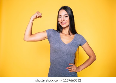 Sport, healthy lifestyle, gym, good body condition, women health, fitness concepts. Close up Portrait of Young cute sporty smiling brunette woman while she shows her arms and biceps on camera - Shutterstock ID 1157660332