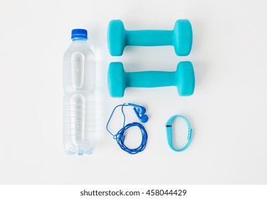 sport, healthy lifestyle and objects concept - close up of dumbbells, fitness tracker, earphones and water bottle over white background - Powered by Shutterstock