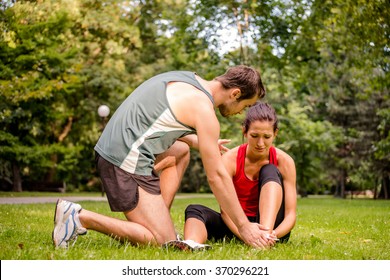 Sport Injury - Young Fitness Woman Holding Her Ankle  With Pain, Man Is Helping