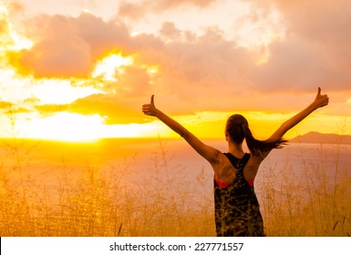 Sport and life achievements and success concept.. Sporty girl raising arms towards beautiful glowing sunshine. 