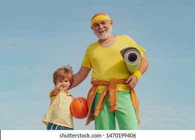 Sport For Little Children. Senior Man And Child In Family Health Club. Senior Man And Child Exercising On Blue Sky. Grandfather Helping Child Exercising