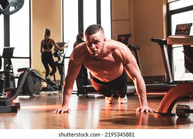 Sport Man Doing Push Ups Exercise, Pushup Crunch. Portrait Of Young Athlete Doing Exercise With Dumbbell At The Gym. Crossfit, Sport And Healthy Lifestyle Concept.