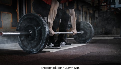 Sport. Man lifting deadlift in the gym with barbell. Dramatic interior with smoke.