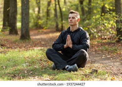 Sport man meditates in the lotus position in the autumn forest.