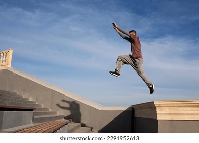 Sport man performing parkour tricks in urban space. Parkour athlete jumping high over stairs outdoors. Extreme sports, outdoor free running parkour or healthy lifestyle concept - Powered by Shutterstock