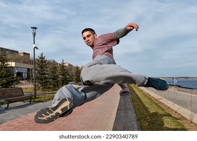 Sport man practicing parkour in urban space. Parkour athlete jumping over the railing. Active lifestyle. Outdoor acrobatics - Powered by Shutterstock