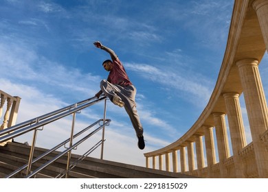 Sport man practicing parkour in urban space. Parkour athlete in sportswear jumping on stairs over the railing. Free runner have workout city street. - Powered by Shutterstock