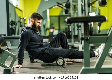 Sport man Using black Foam Roller for Muscle and Fascia Stretching leg - Male athlete relieve sore muscles after a training workout at gym - health and fitness sport body care concept