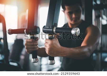 Sport man using sport machine exercise at gym. Asian body building for muscle training.  Sport health gym concept