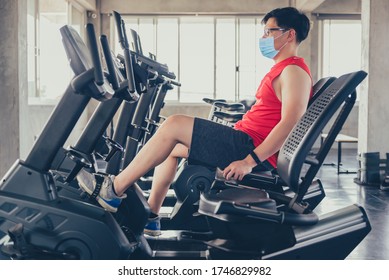 Sport man wear face mask for work out. Exercise bike at fitness gym. Social distancing and wellness. Fit and firm for healthy. Mind-body improvements. New normal and life after COVID-19. - Powered by Shutterstock